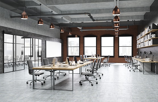 A large office space with desks and chairs under the spot lights
